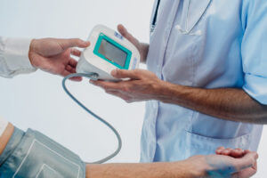 A cardiologist checks a patient's pulse with a sphygmomanometer to assess heart health.