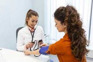 Woman getting her blood pressure checked at her annual physical exam with her primary care physician.